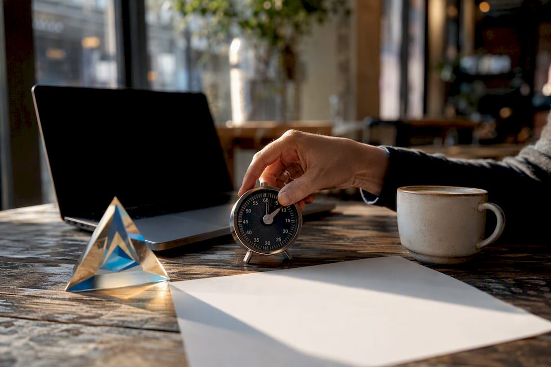 Hand adjusting timer beside Blue Prysm prism on desk